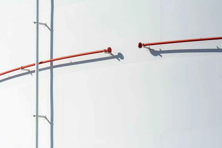 A close-up of a white industrial surface with a red pipe casting a shadow. Minimalist design.